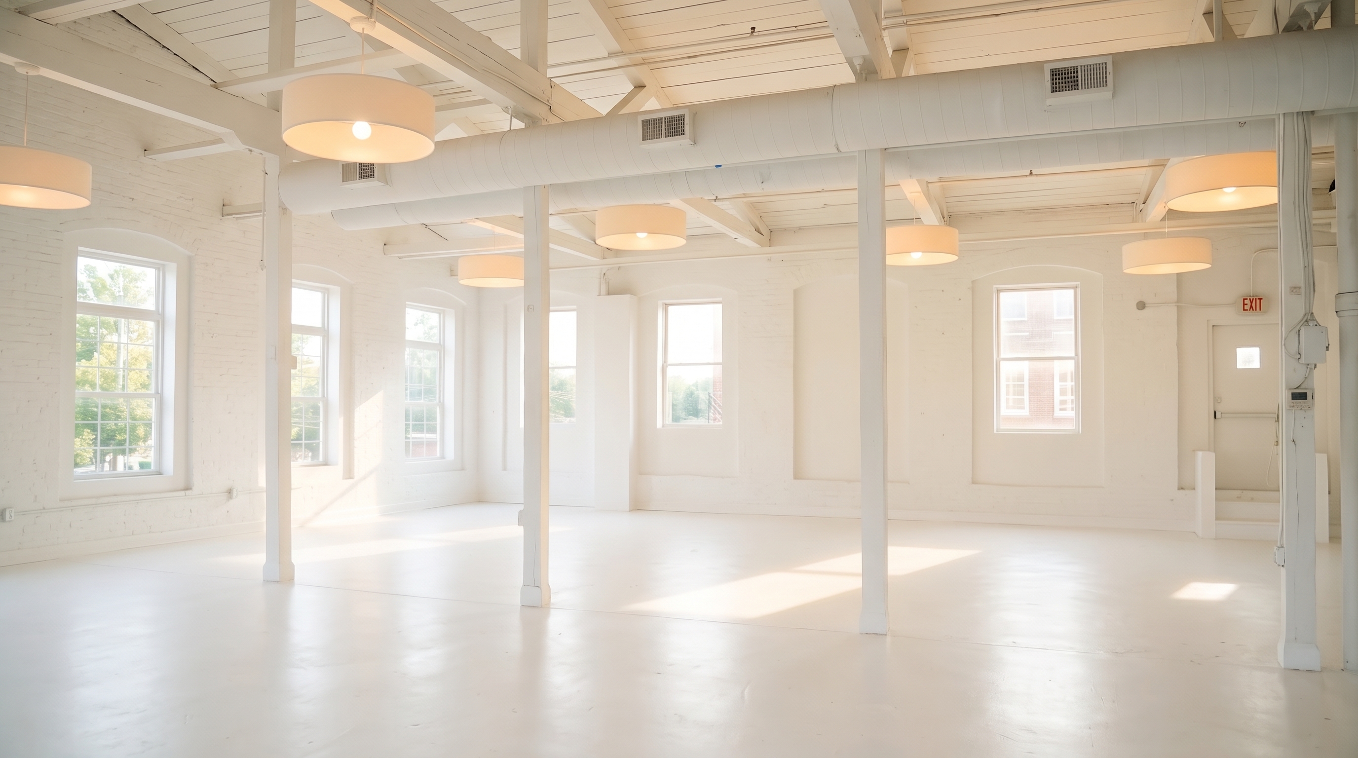 Empty white industrial hall with broad windows, structural columns and daylight